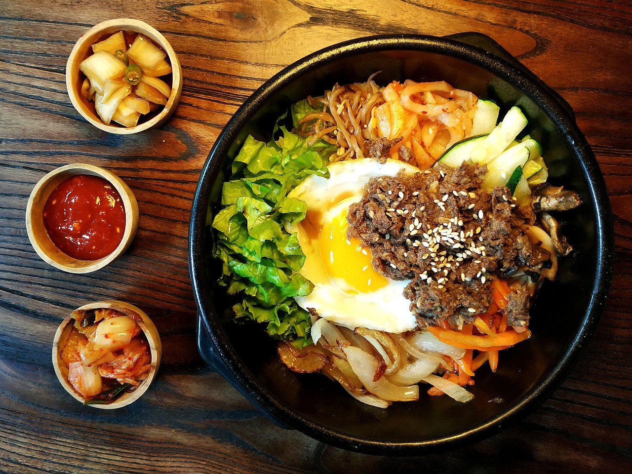 Colorful Korean Bibimbap rice bowl with assorted sautéed vegetables, marinated beef, fried egg, and spicy gochujang sauce