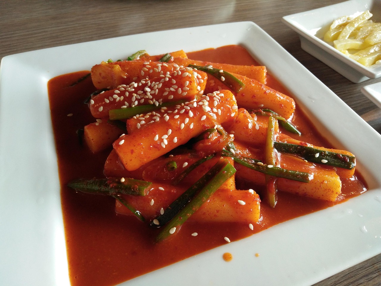 Traditional Korean street food Tteokbokki served hot with scallions and fish cakes in a sizzling pan