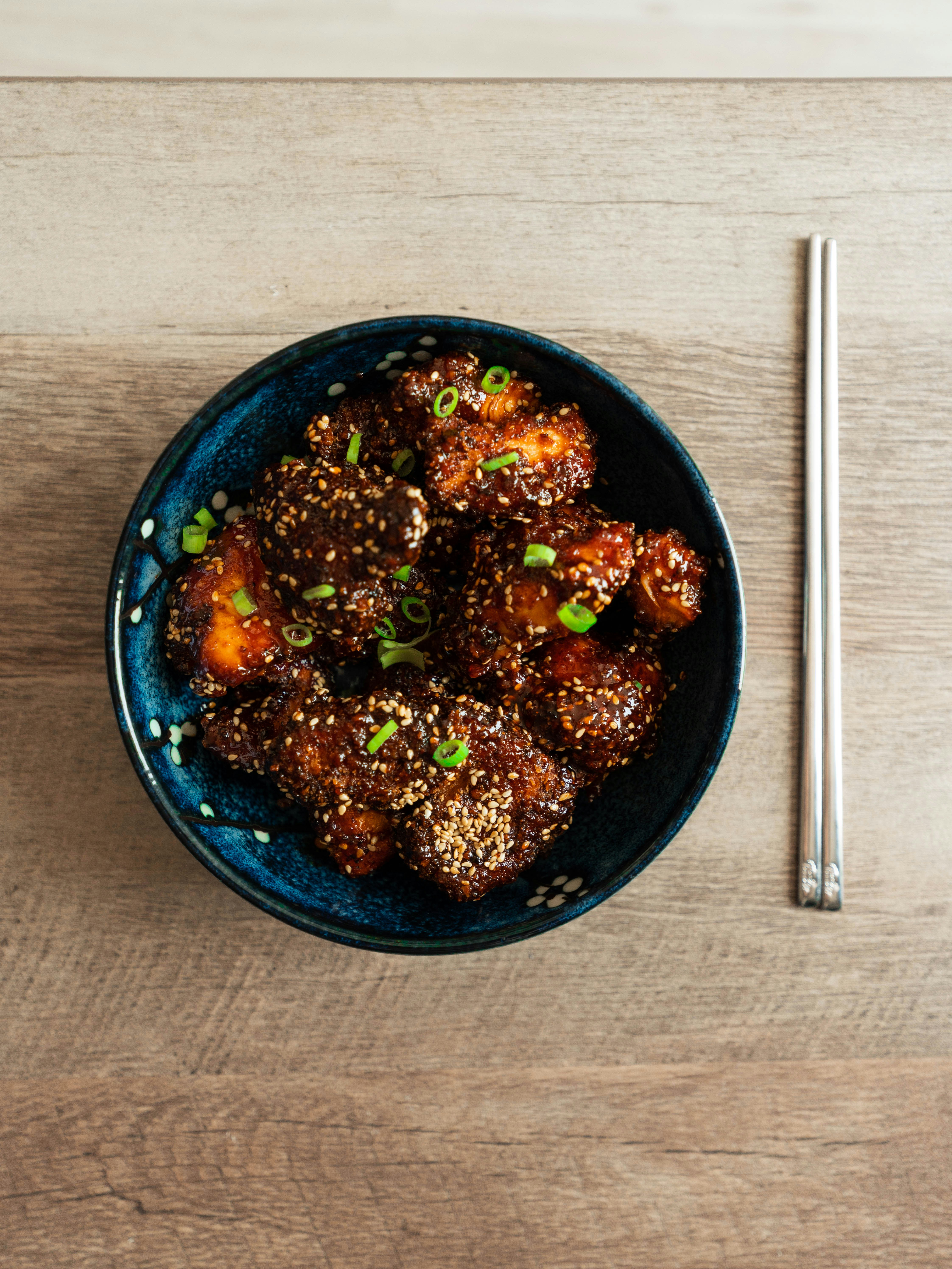 Crispy Korean fried chicken wings coated in sticky soy garlic sauce, garnished with sesame seeds.